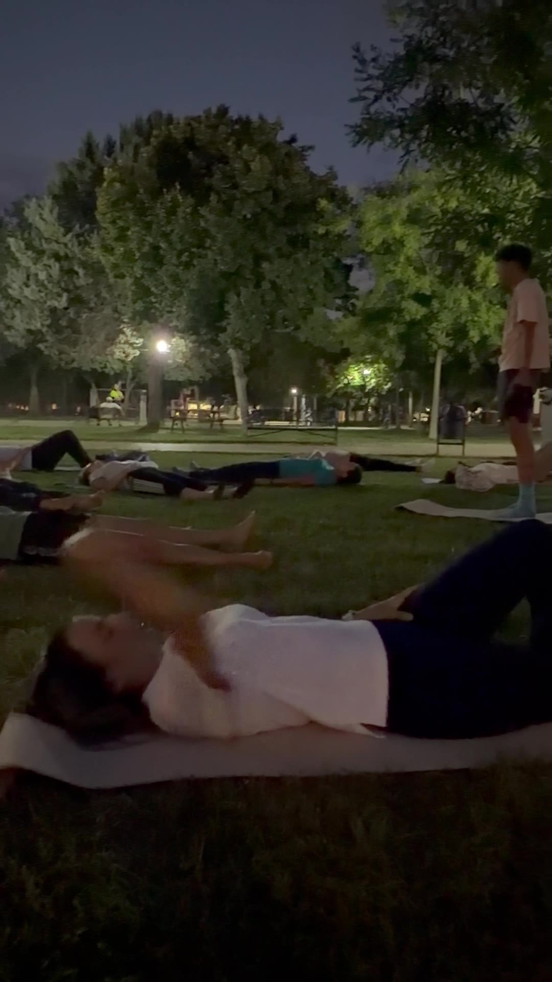 El parque de noche con las participantes descansando sobre el césped